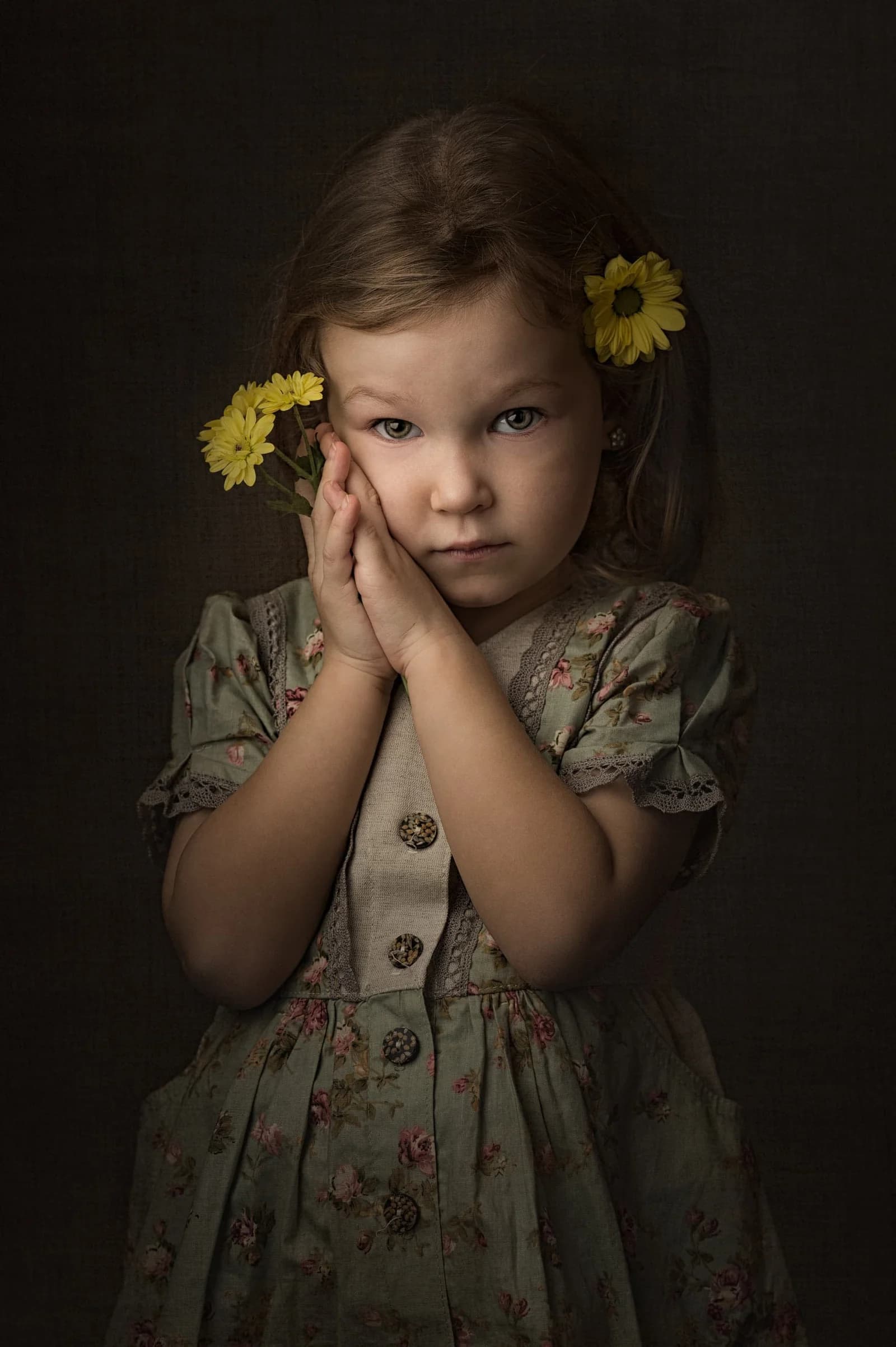 Mädchen in geblümtem Vintage-Kleid hält gelbe Blüten an die Wange, gemäldeartiges Fine-Art-Porträt mit warmem Streiflicht